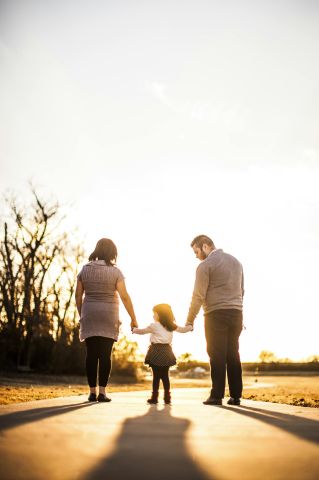 A family of three walks hand in hand at sunset, enjoying togetherness and warmth.